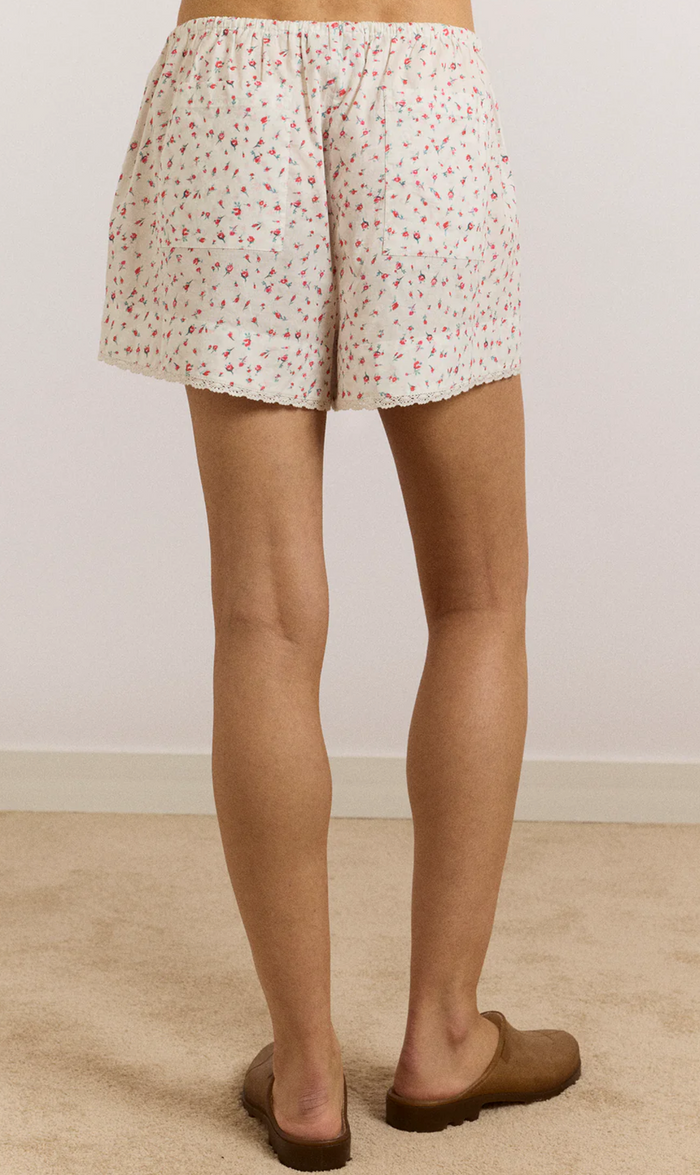 Person wearing floral shorts on a plain background