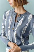 Woman wearing a blue cardigan with white fish pattern against a light blue background