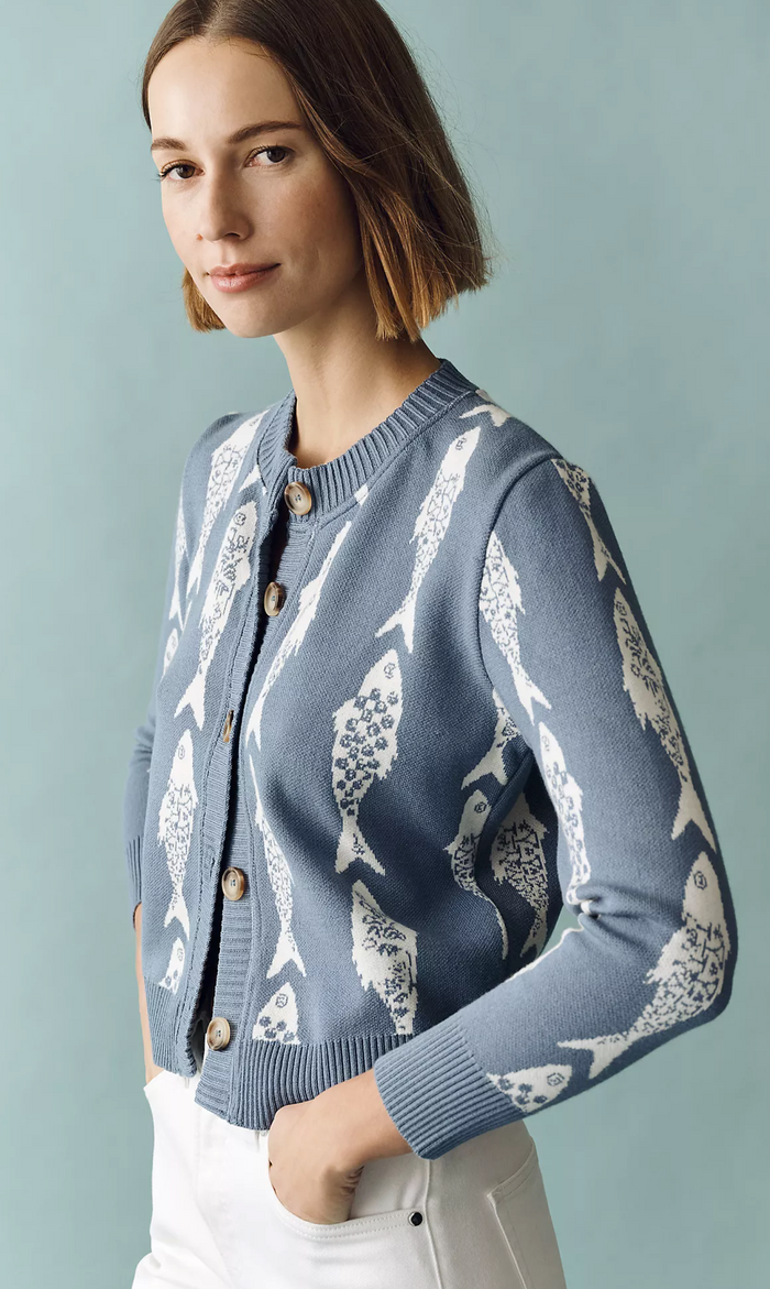 Woman wearing a blue cardigan with white whale pattern against a light gray background
