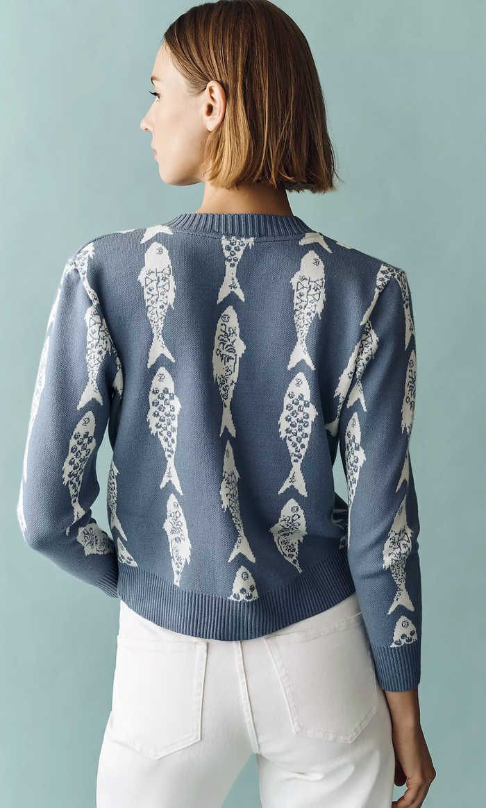 Person wearing a blue sweater with fish pattern against a light gray background
