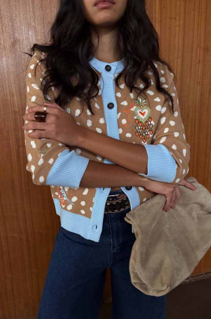 Person wearing a patterned cardigan with a wooden background