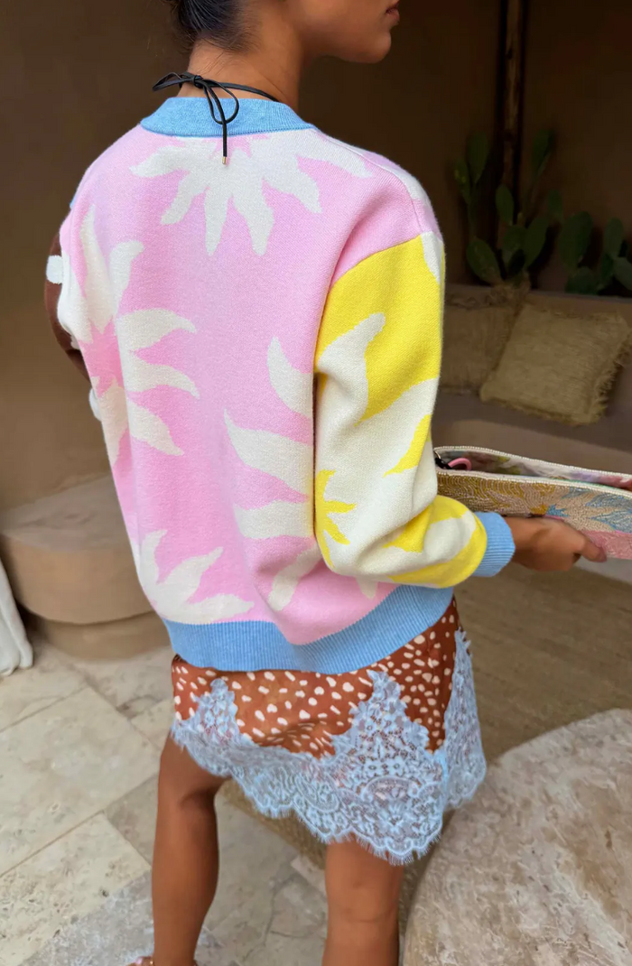 Person wearing a colorful jacket with pink, yellow, and blue patterns in an indoor setting.