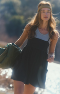 Woman in a black romper and headband holding a green bag outdoors
