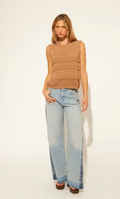 Woman wearing a brown sleeveless knitted top and light blue jeans on a white background