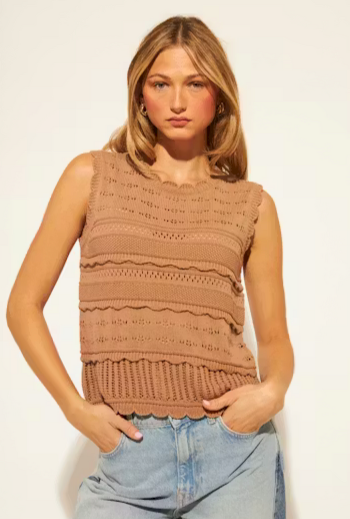 Woman wearing a brown sleeveless knitted top against a plain background