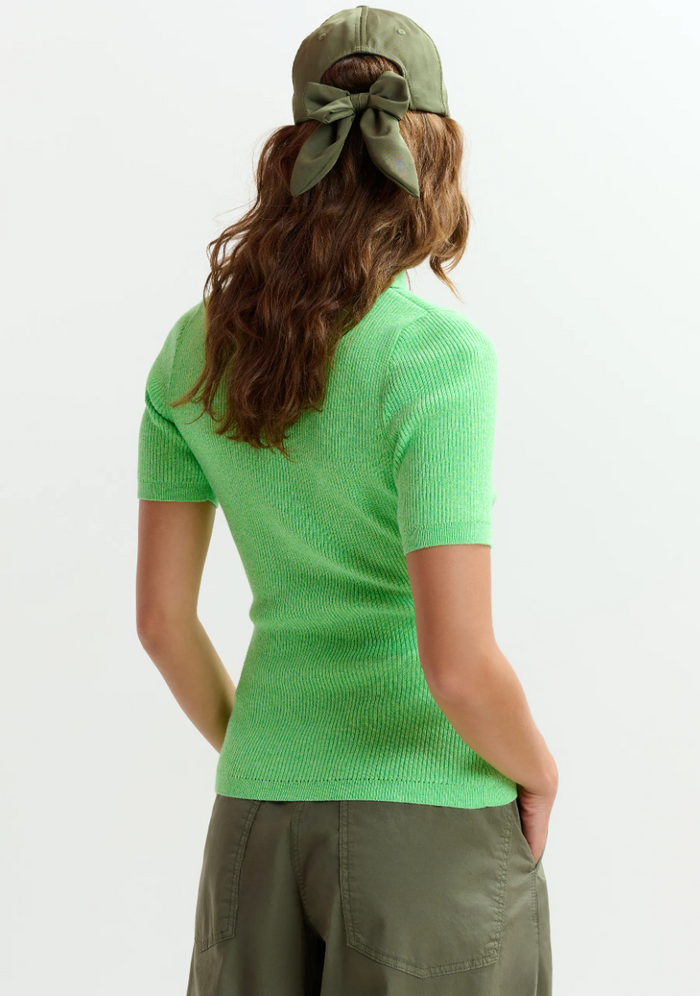 Woman wearing a green sweater and cap on a white background