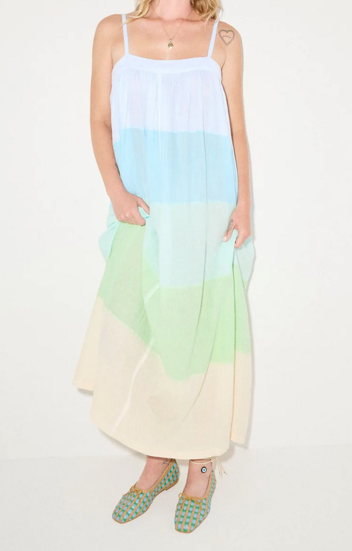 Woman wearing a gradient dress with blue, green, and yellow colors on a white background