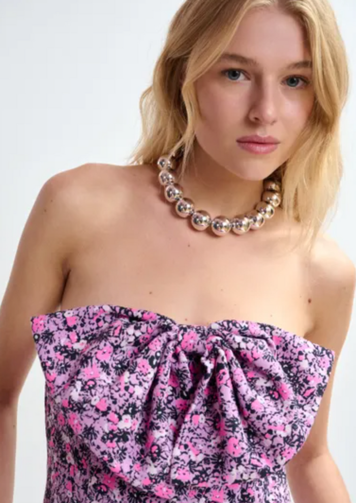Woman wearing a strapless floral dress with a necklace on a white background