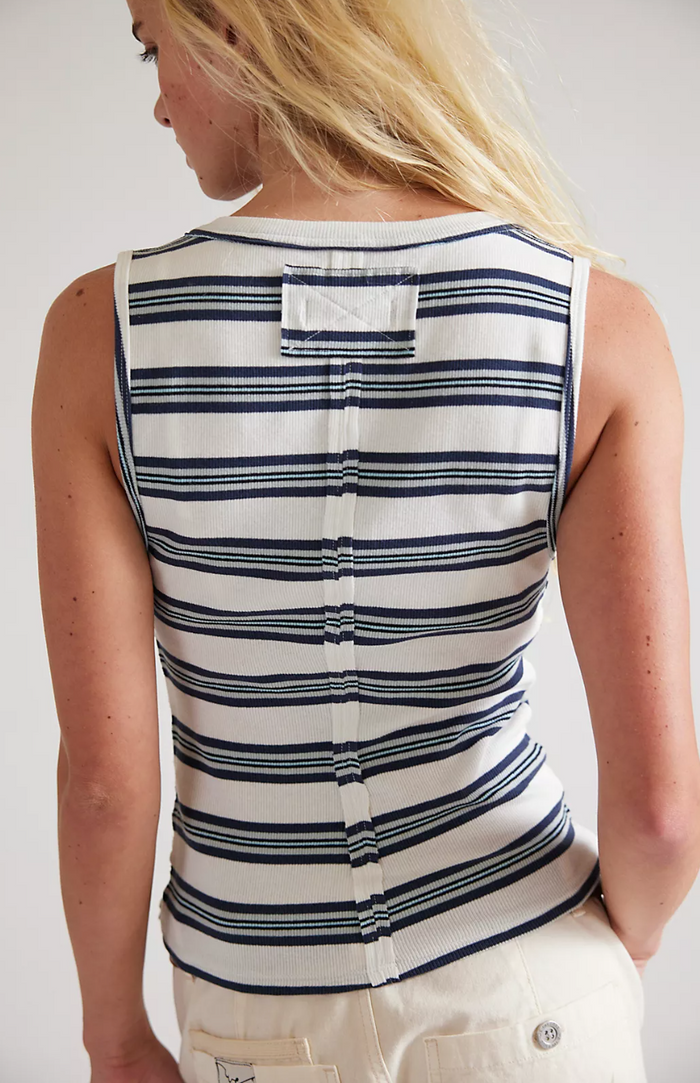 Person wearing a striped sleeveless shirt with a plain background