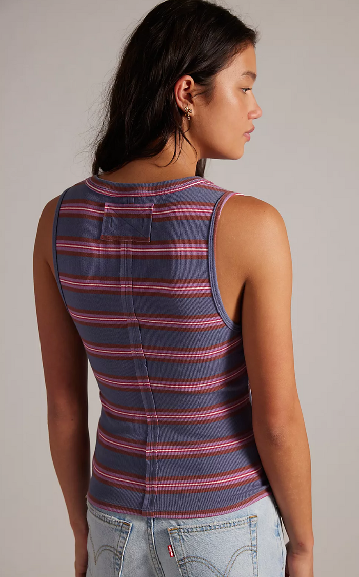 Woman wearing a striped tank top and jeans on a plain background