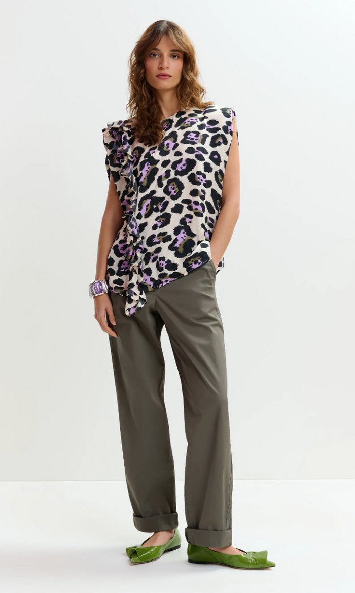 Woman wearing a leopard print top and green pants on a white background
