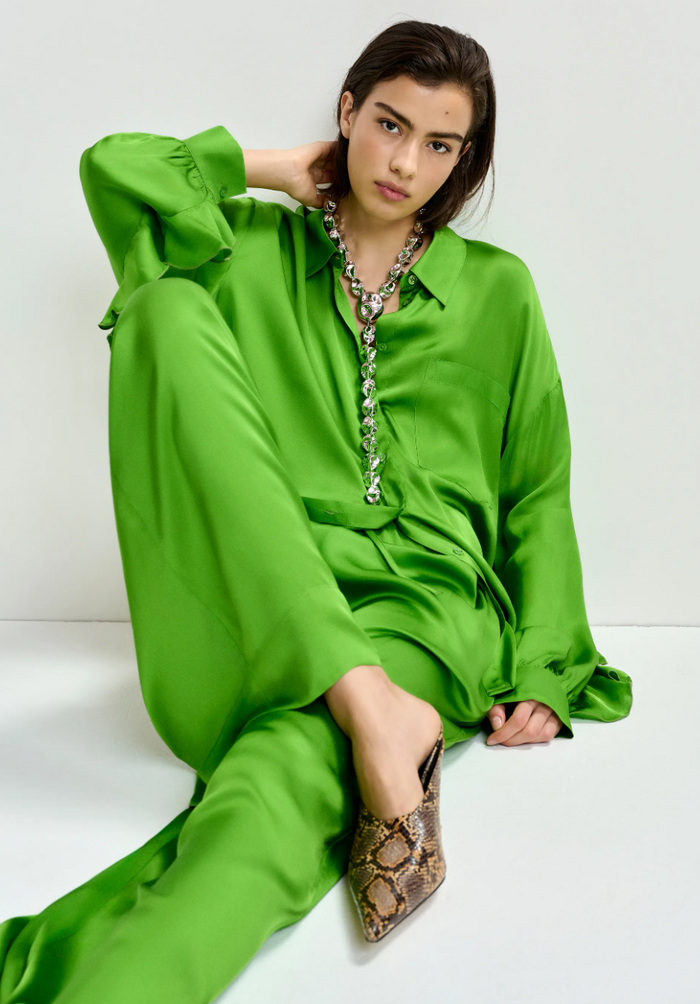 Woman wearing a green outfit with snake print shoes on a white background