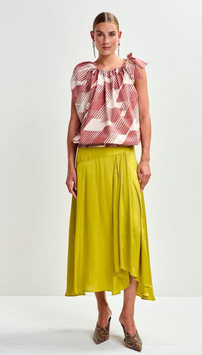 Woman wearing a patterned top and yellow skirt on a white background