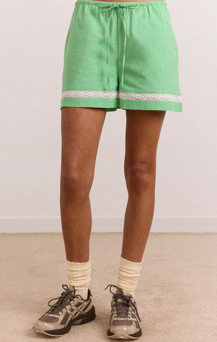 Green shorts with lace trim worn by a person on a plain background