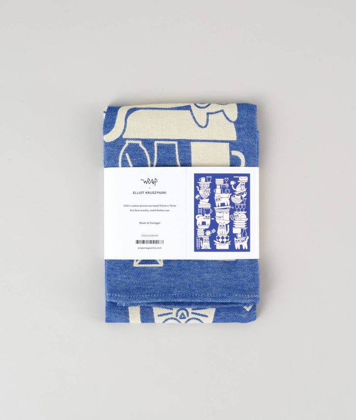 Kitchen Cats Cotton Tea Towel in paper sleeve showing name of designer Elliot Kruszynski, 100% woven cotton material, and that it is made in Portugal.