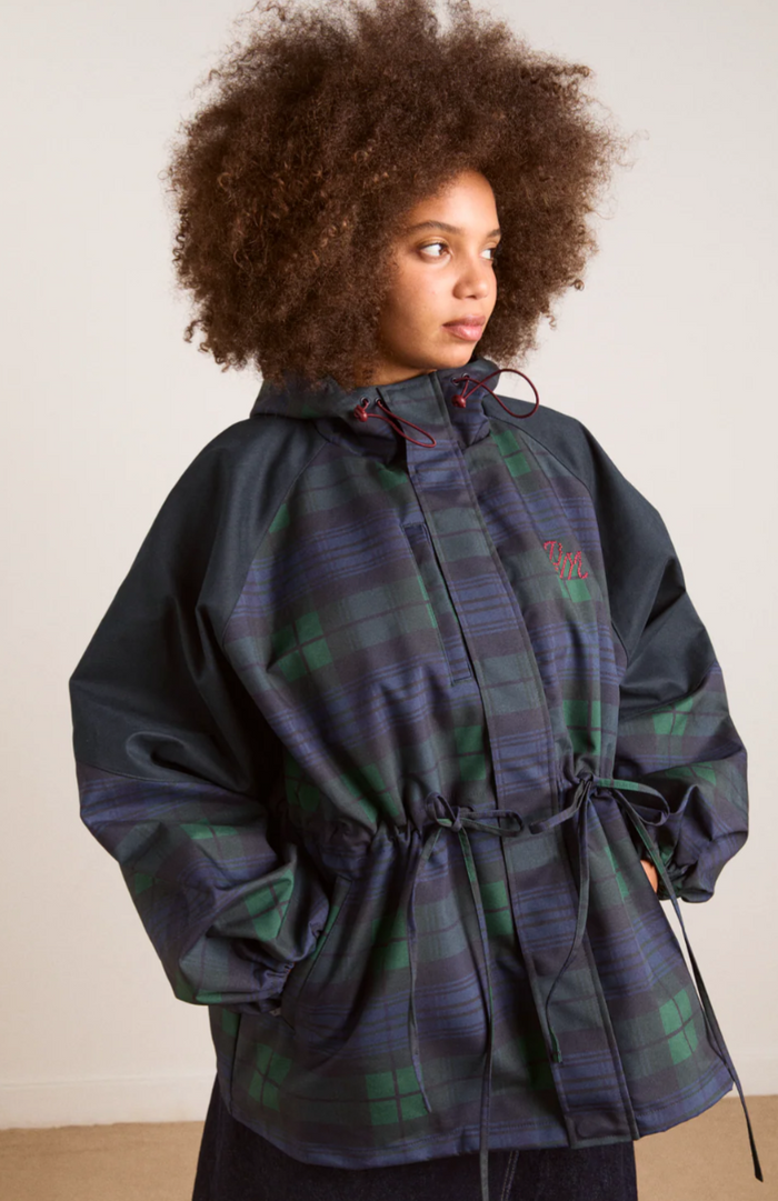 Person wearing a plaid jacket with a hood against a plain background