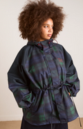 Person wearing a plaid jacket with a hood against a plain background
