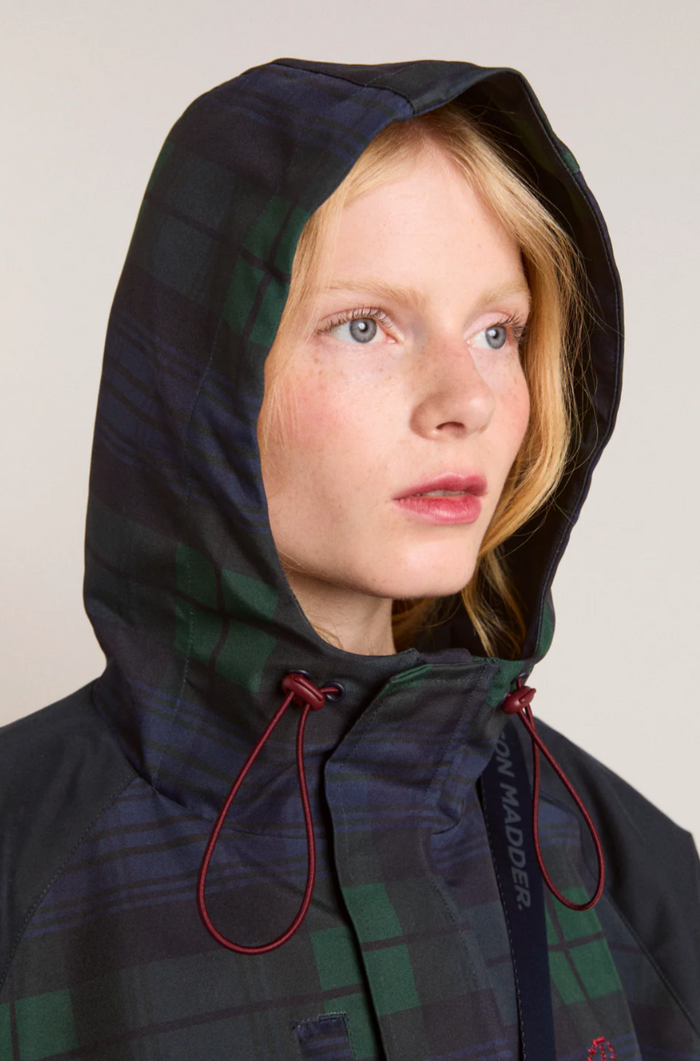 Person wearing a plaid hooded coat with visible brand name on a plain background