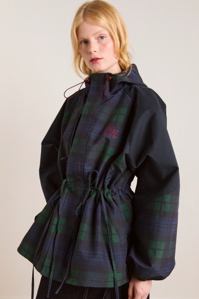 Person wearing a dark blue and green plaid coat on a plain background