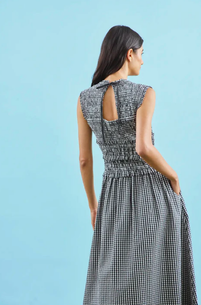 Woman wearing a black and white checkered dress against a light blue background