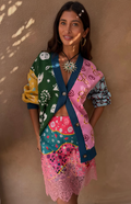 Woman wearing a colorful patterned outfit against a beige wall.
