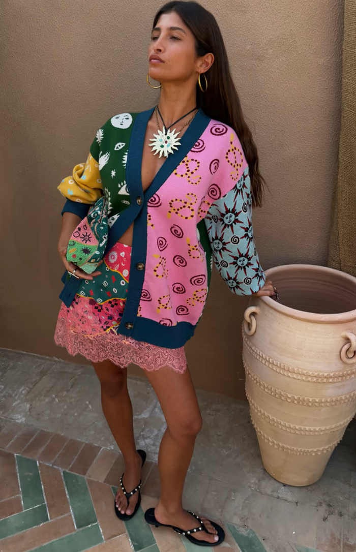 Woman wearing a colorful patterned cardigan standing next to a large ceramic pot.