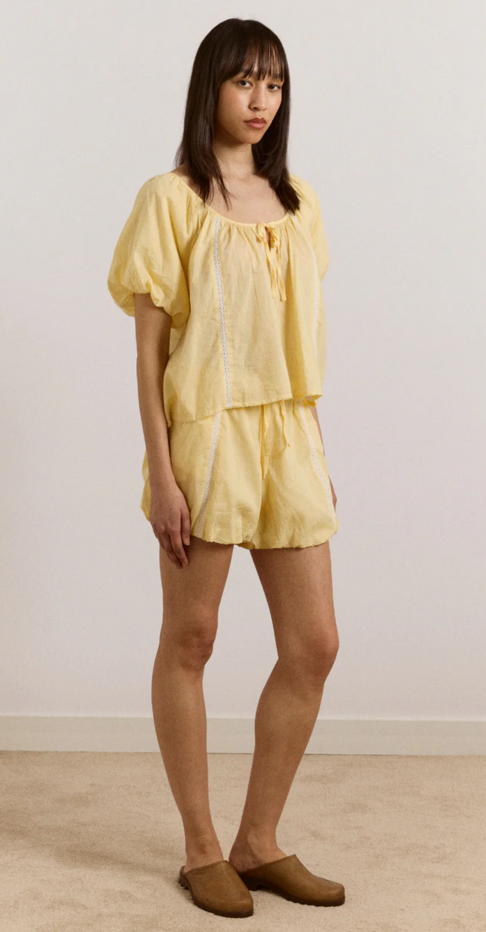 Woman wearing a yellow outfit against a plain background
