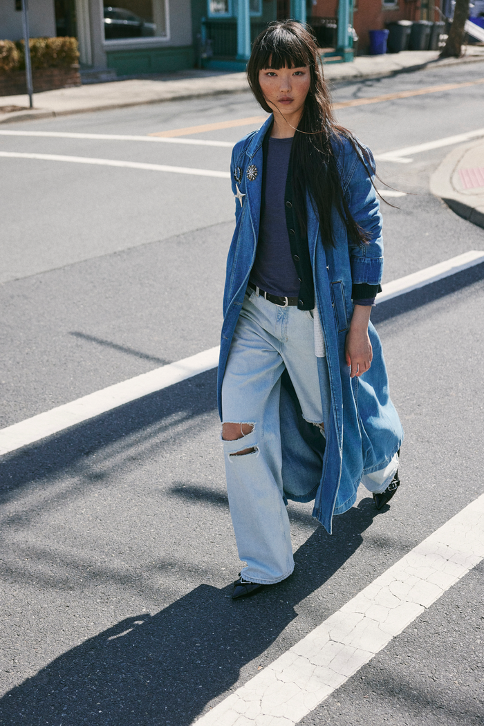 Person wearing a blue coat and ripped jeans on a street
