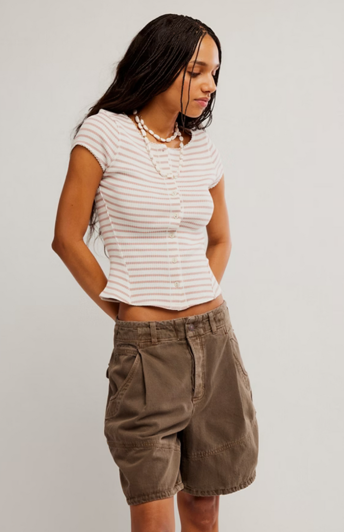 Woman wearing a striped shirt and cargo shorts on a plain background