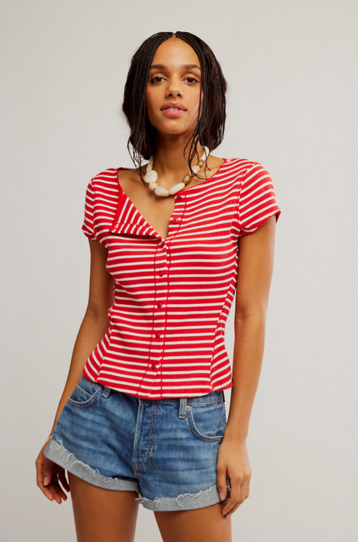 Woman wearing a red and white striped shirt and denim shorts on a plain background