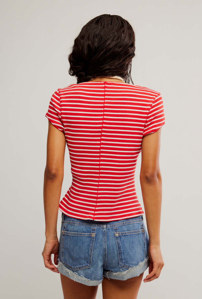 Person wearing a red and white striped shirt and denim shorts on a plain background