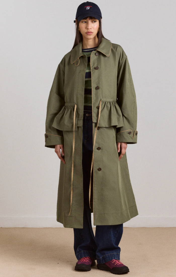 Person wearing a long sage coat with a plain background