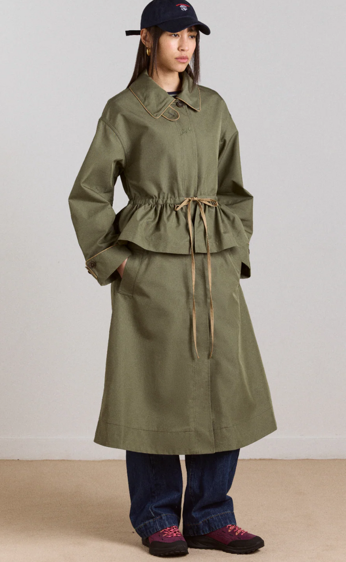 Person wearing a sage trench coat with a white background
