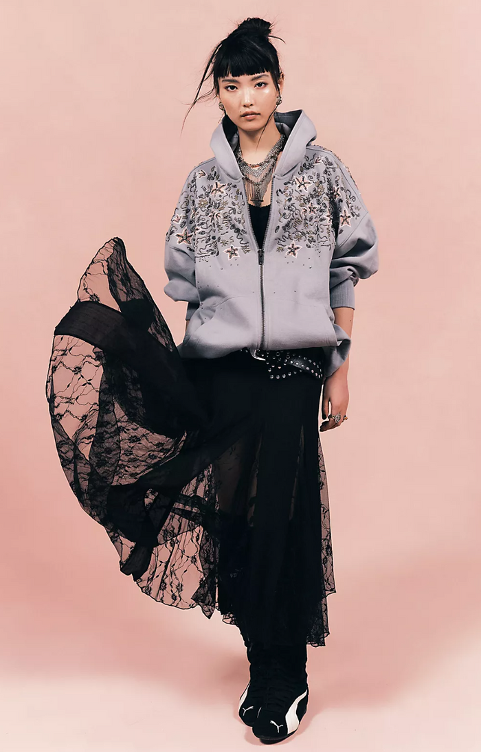 Woman wearing a gray floral hoodie and black lace dress on a pink background