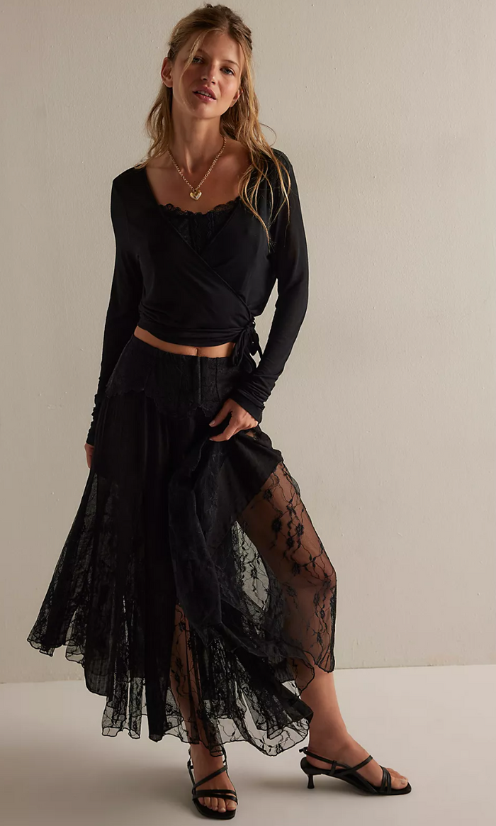Woman wearing a black outfit with a sheer overlay skirt against a neutral background