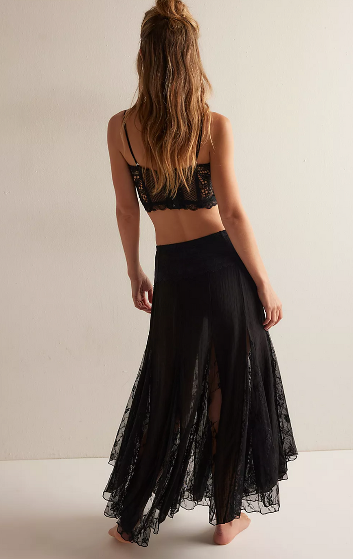 Woman wearing a black lace top and skirt set on a plain background