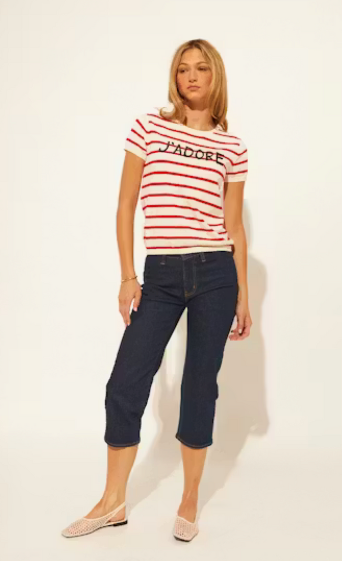 Woman wearing a red and white striped shirt with 'J'adore' text and dark blue jeans on a white background