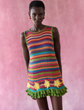 Model wearing a colorful striped dress with floral details against a pink background