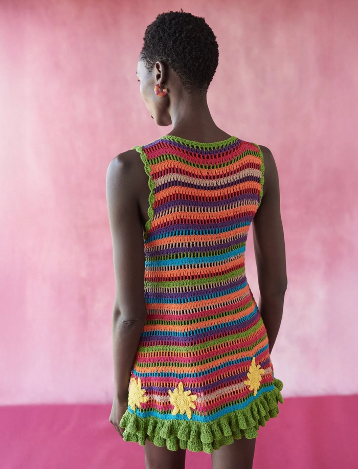 Woman wearing a colorful striped dress against a pink background