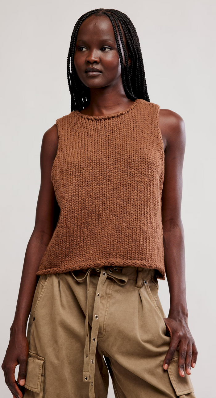 Woman wearing a emperador knitted sleeveless top and beige cargo pants on a plain background