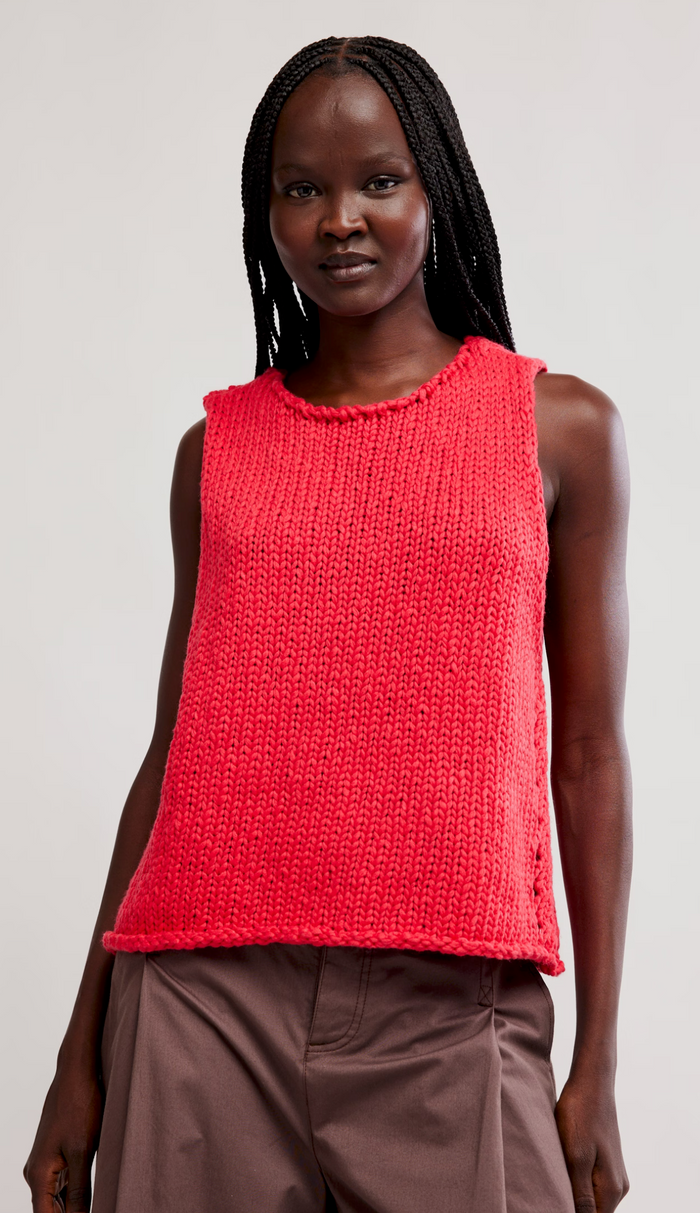 Woman wearing a sour sweet knitted sleeveless top against a plain background