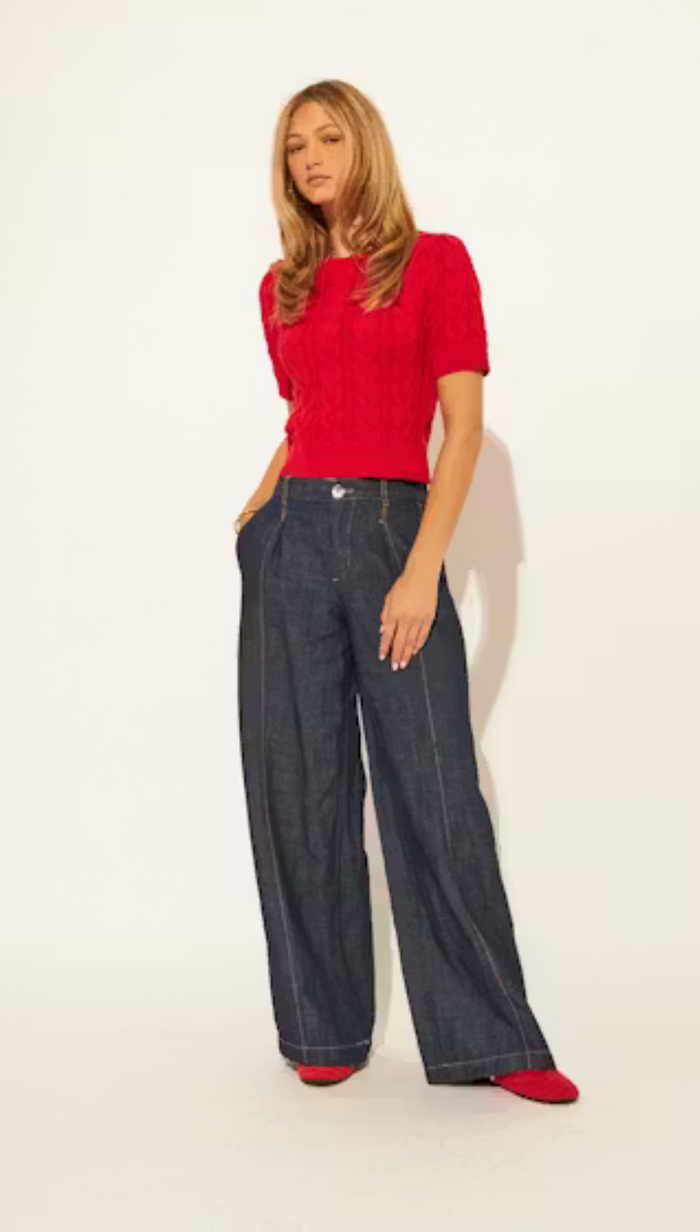 Woman wearing a red top and blue jeans on a white background