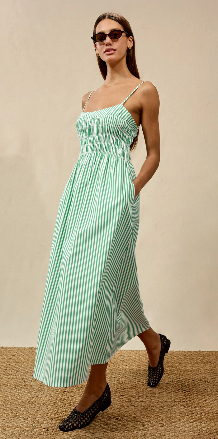 Woman wearing a light green striped dress against a beige background