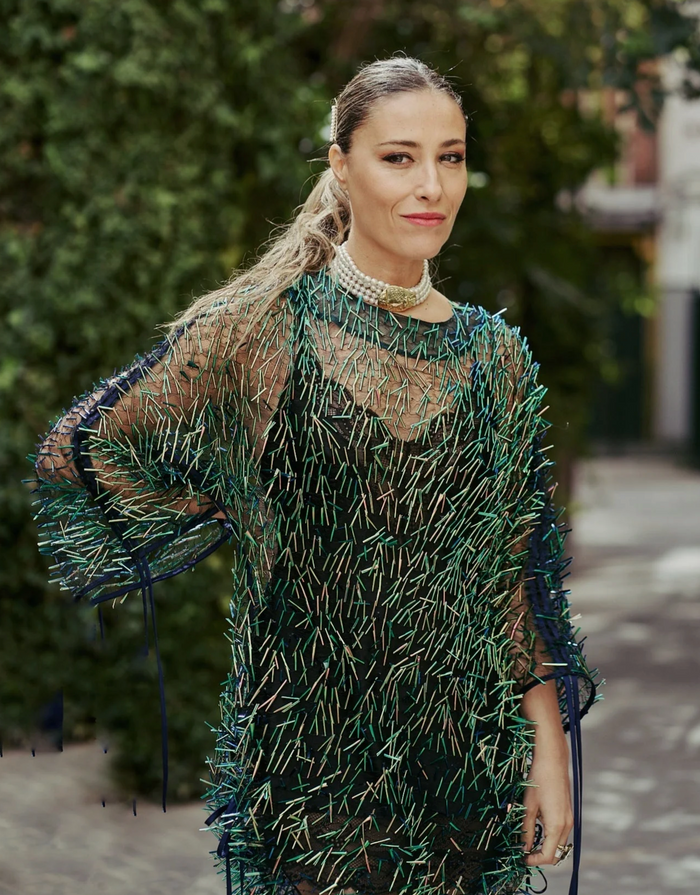 Woman wearing a green and black patterned dress with a blurred outdoor background