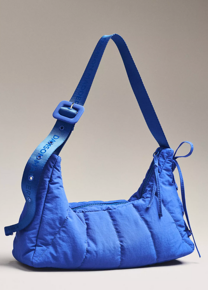 Blue quilted handbag with a strap on a beige background