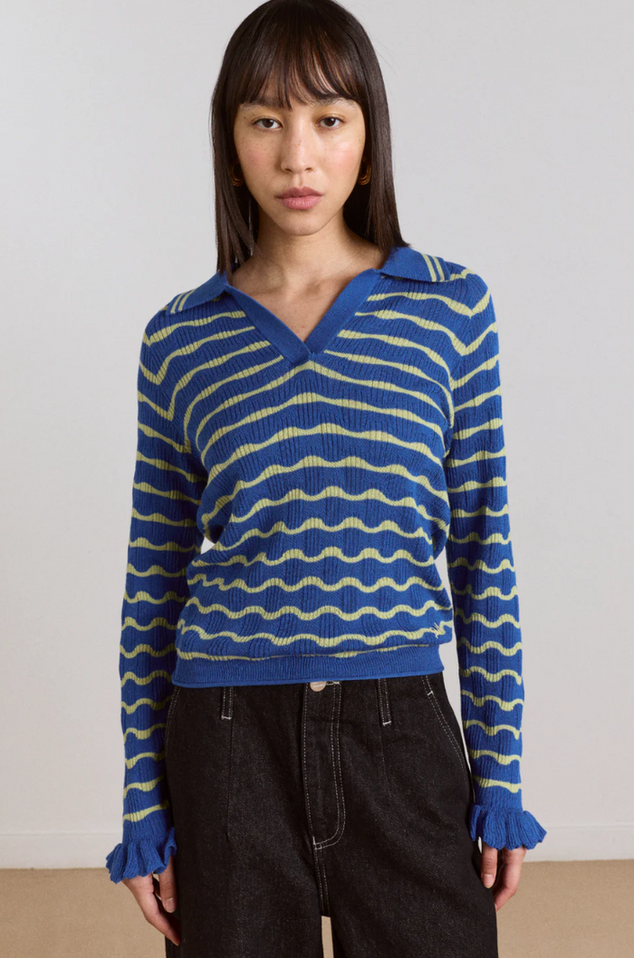 Woman wearing a blue and yellow striped sweater against a plain background