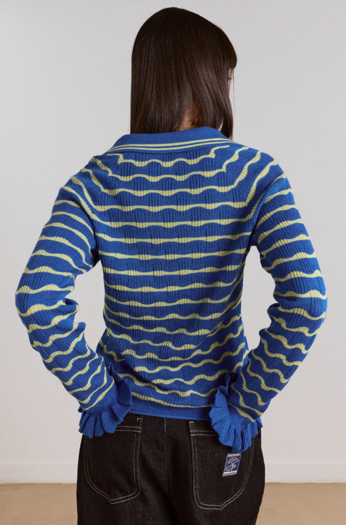 Person wearing a blue and yellow striped sweater with a plain background