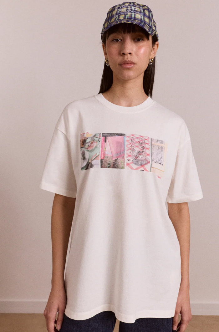 Person wearing a white t-shirt with a graphic design on a plain background