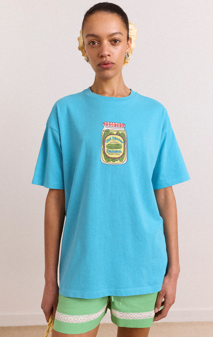 Person wearing a blue t-shirt with a logo and green shorts on a plain background