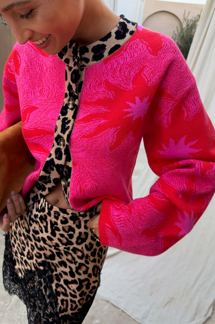 Person wearing a bright pink jacket with a leopard print pattern.
